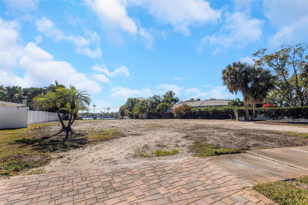 A vacant, sandy residential lot features a brick paver driveway and scattered palm trees — 105 ESTADO WAY NE, ST PETERSBURG, FL
