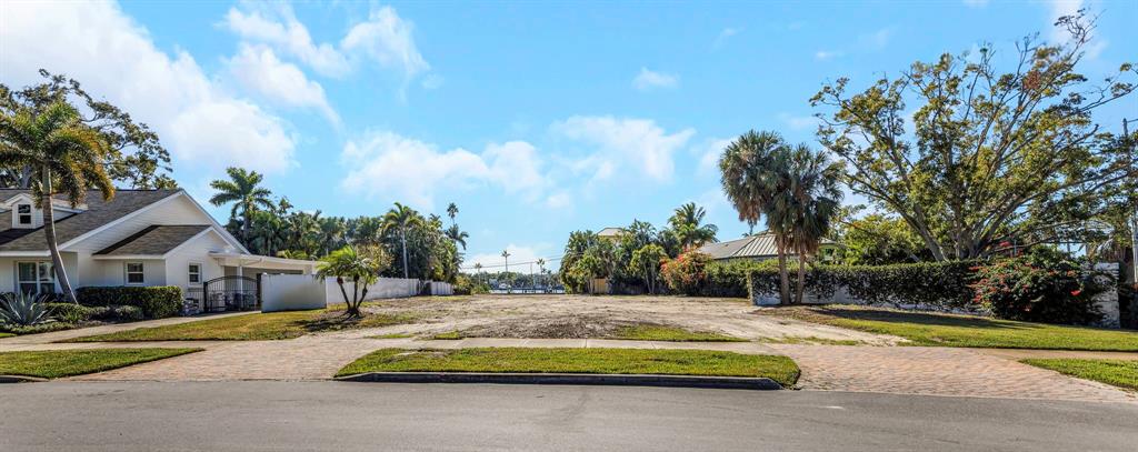 A vacant, sandy residential lot sits between two houses on a sunny, paved street — 105 ESTADO WAY NE, ST PETERSBURG, FL