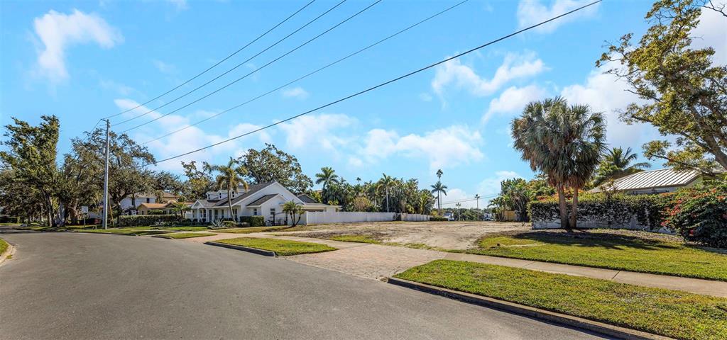 A vacant residential lot sits between a white house and a fenced property with trees — 105 ESTADO WAY NE, ST PETERSBURG, FL