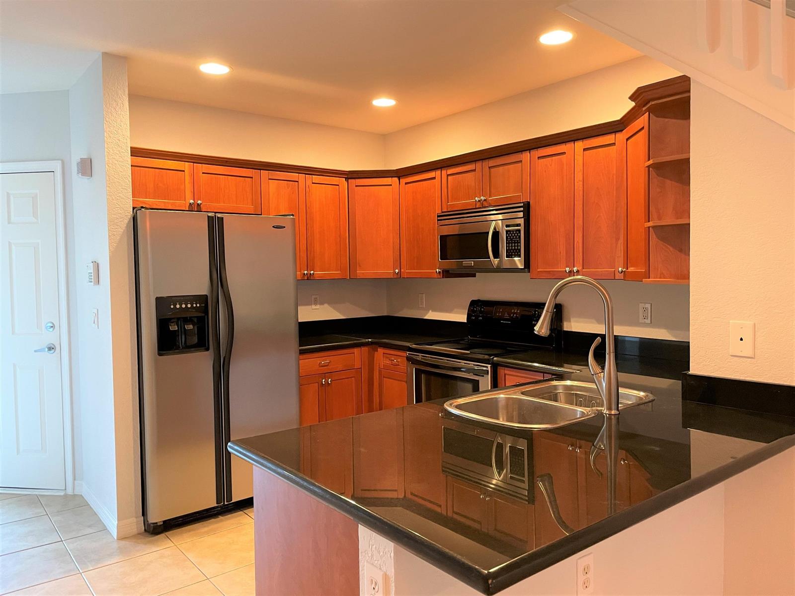 A kitchen features wood cabinets, black countertops, stainless steel appliances, and a double-basin sink — 602 S Federal Highway # 5, FL 33460, FL