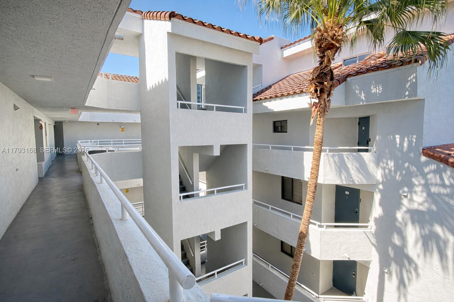 An exterior view shows a multi-story apartment building with open-air walkways and a palm tree — 8305 SW 152nd Ave # 411, Miami FL 33193, MIAMI, FL