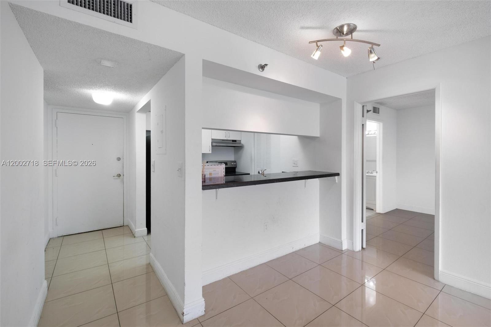A kitchen pass-through window with a breakfast bar overlooks a tiled living area — 800 N Miami Ave # 1110, Miami FL 33136, MIAMI, FL