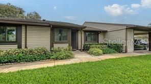 A single-story house with beige horizontal siding, a covered carport, and a front lawn — 5911 39TH AVENUE W, BRADENTON, FL