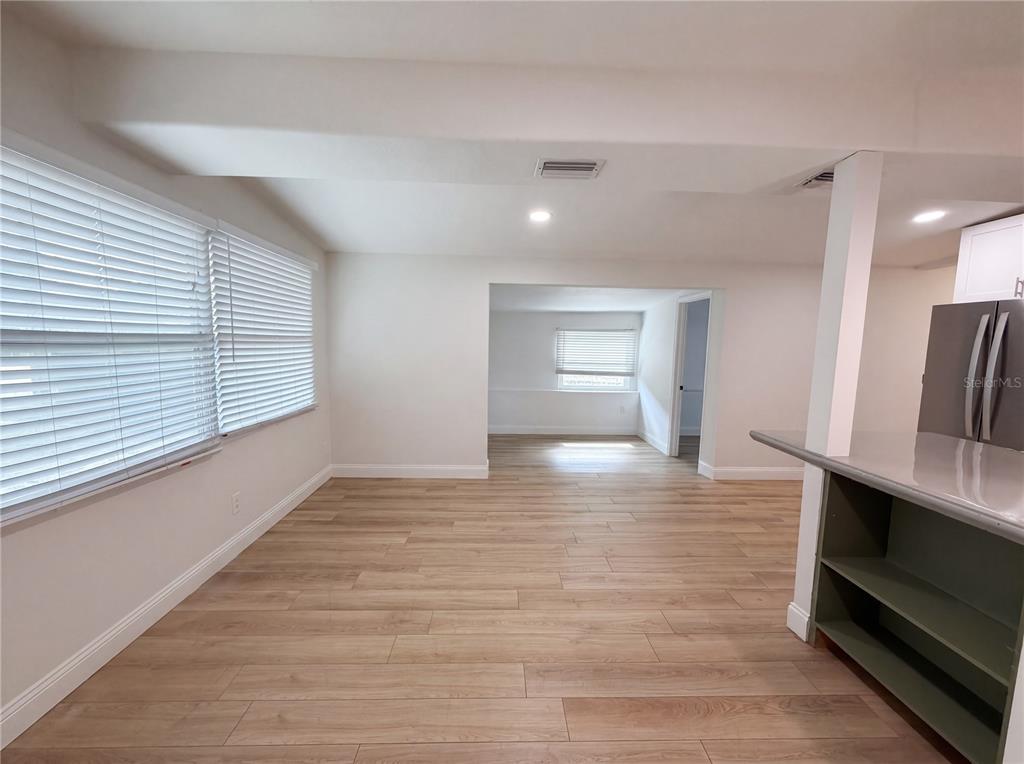 A bright room with light wood-look flooring, white walls, and a view into an adjacent space — 2905 E CHELSEA STREET, TAMPA, FL