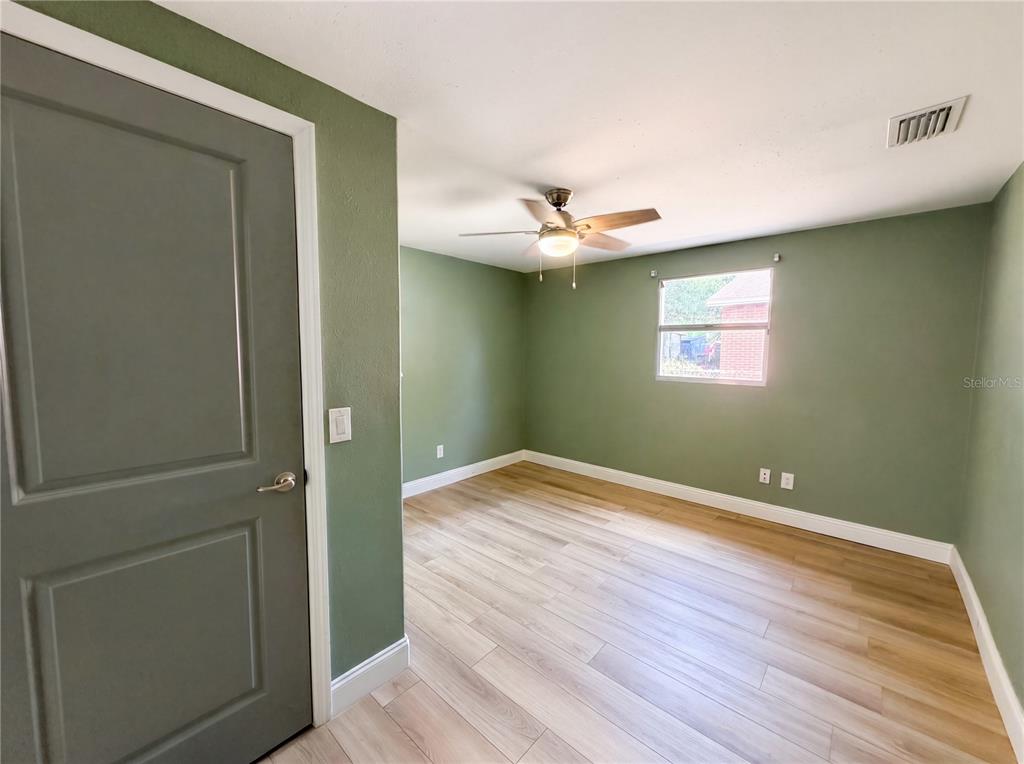 An empty bedroom features sage green walls, light wood-look flooring, and a ceiling fan — 2905 E CHELSEA STREET, TAMPA, FL