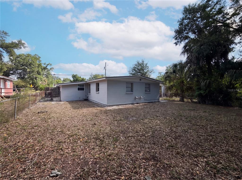 The exterior of a light gray, single-story house sits on a large, leaf-covered lot — 2905 E CHELSEA STREET, TAMPA, FL