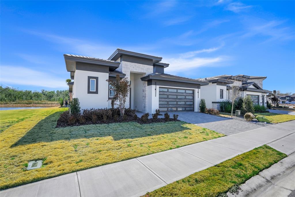A modern single-story house with a stone facade, dark trim, and a glass-paneled garage door — 3060 KENSINGTON AVENUE, DAVENPORT, FL