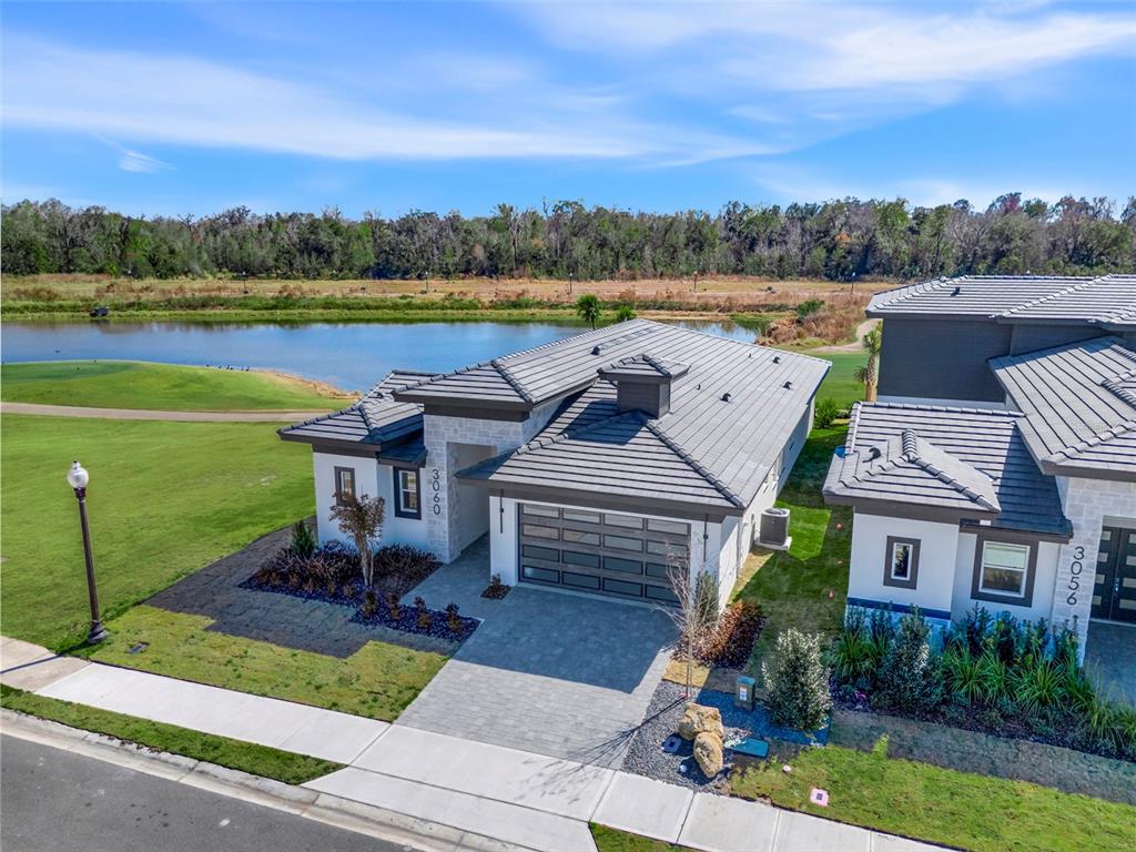 An aerial view shows two modern houses with gray tile roofs next to a lake — 3060 KENSINGTON AVENUE, DAVENPORT, FL