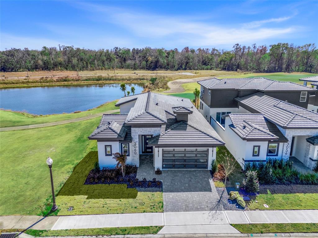 An aerial view shows two modern houses with gray tile roofs next to a pond — 3060 KENSINGTON AVENUE, DAVENPORT, FL