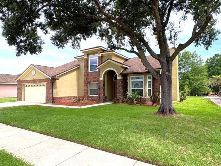 A tan, single-story house with a brown roof and a large tree in the front yard — 2813 ROLLING BROAK DRIVE, ORLANDO, FL