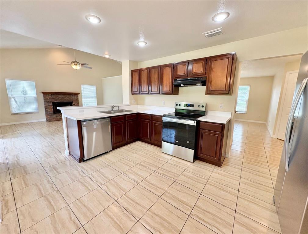 A kitchen with dark wood cabinets, stainless steel appliances, and light tile flooring — 2813 ROLLING BROAK DRIVE, ORLANDO, FL