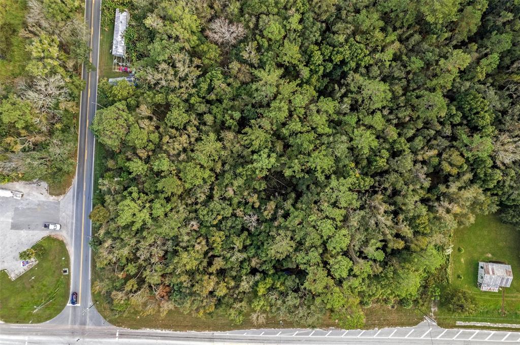 An aerial view shows a wooded lot bordered by two roads and a small building — 00 FORT DADE AVENUE, BROOKSVILLE, FL