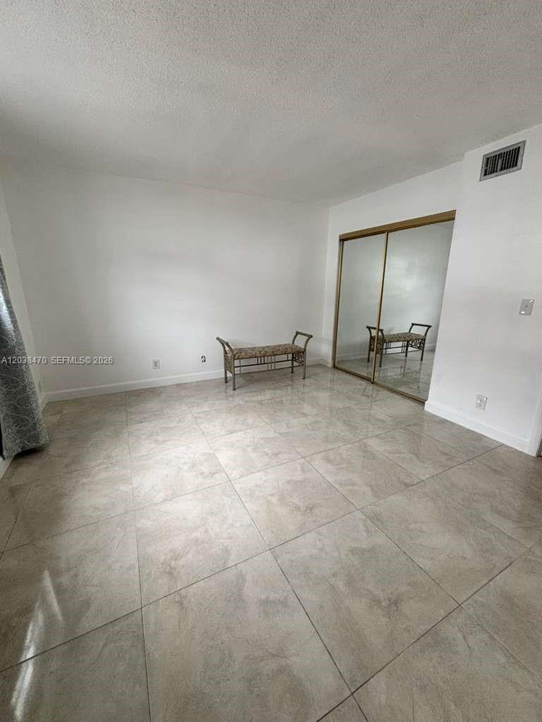 A room with white walls, light-colored tile flooring, and a mirrored sliding closet door — 541 Blue Heron Dr # 215, Hallandale Beach FL 33009, HALLANDALE BEACH, FL
