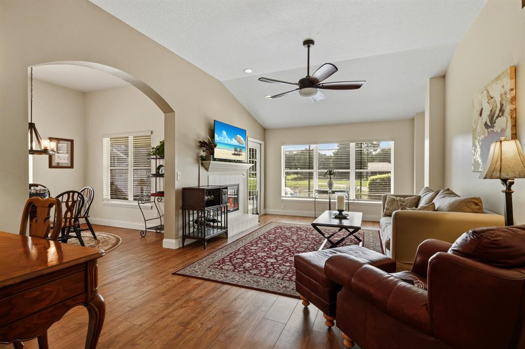 A living room with wood-look flooring, a fireplace, a ceiling fan, and an adjacent dining area — 1750 STAFFORD SPRINGS BOULEVARD, MOUNT DORA, FL