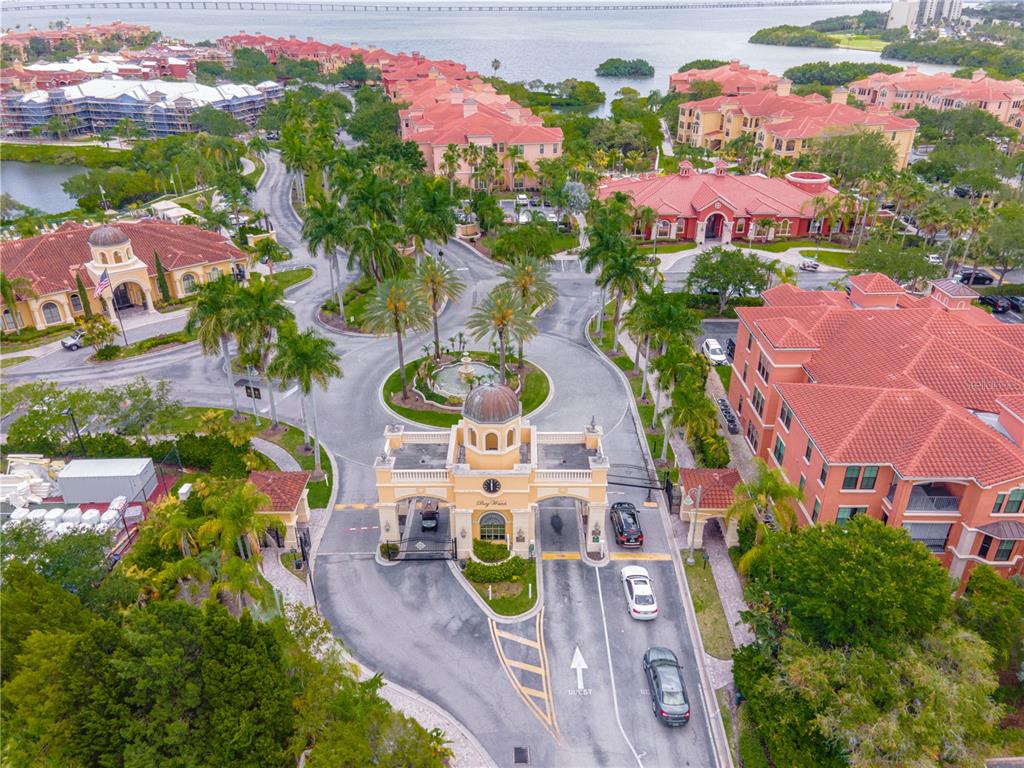 An aerial view shows the gated entrance to a residential community with red-roofed buildings — 2721 VIA MURANO UNIT 324, CLEARWATER, FL
