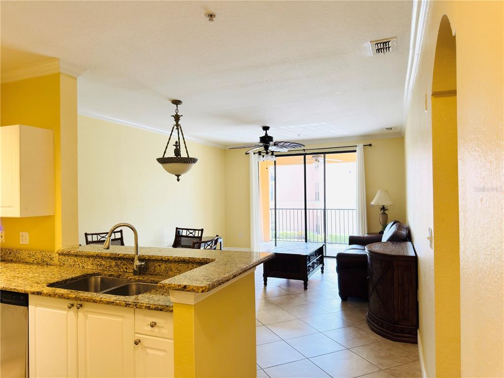 A kitchen with granite countertops overlooks a living area with tile floors and a balcony — 2721 VIA MURANO UNIT 324, CLEARWATER, FL