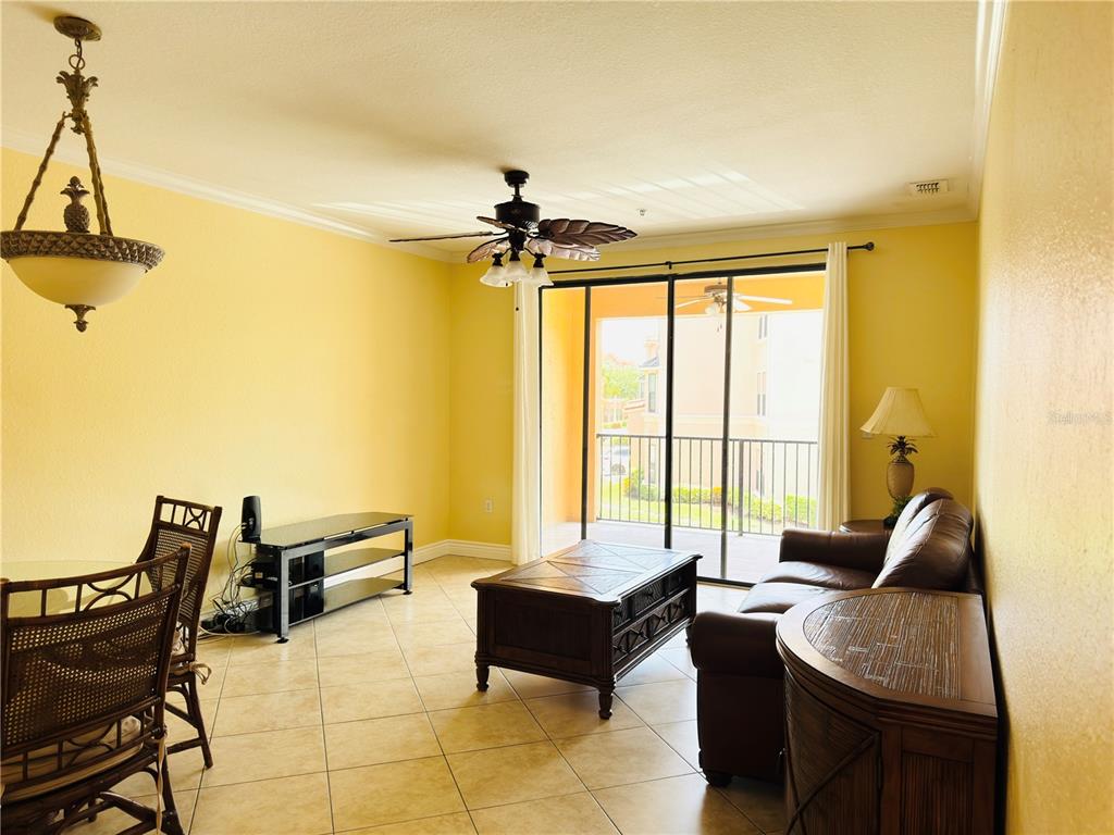 A living room with tile floors, a ceiling fan, and a sliding door to a balcony — 2721 VIA MURANO UNIT 324, CLEARWATER, FL