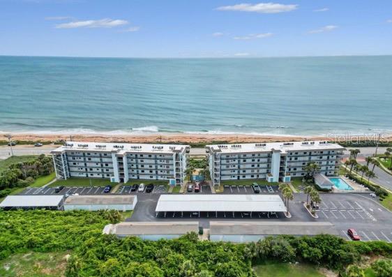 An aerial view of a multi-story beachfront apartment complex with a parking lot and pool — 3180 OCEAN SHORE BOULEVARD UNIT 108, ORMOND BEACH, FL