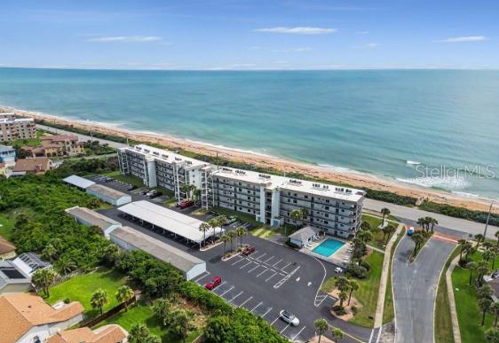An aerial view shows a multi-story beachfront condominium complex with a parking lot and pool — 3180 OCEAN SHORE BOULEVARD UNIT 108, ORMOND BEACH, FL