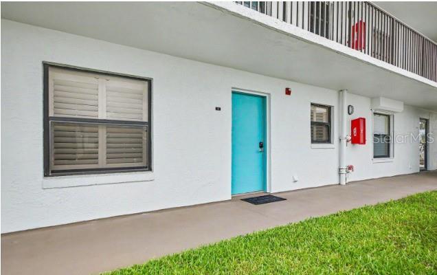 A bright blue front door on a white building exterior with a ground-level walkway — 3180 OCEAN SHORE BOULEVARD UNIT 108, ORMOND BEACH, FL