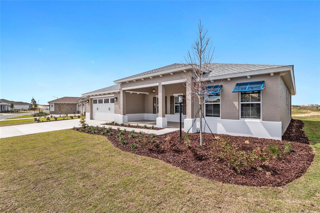 A single-story house with a tan stucco exterior, white trim, and a covered front porch — 10345 SW 82ND PLACE ROAD, OCALA, FL