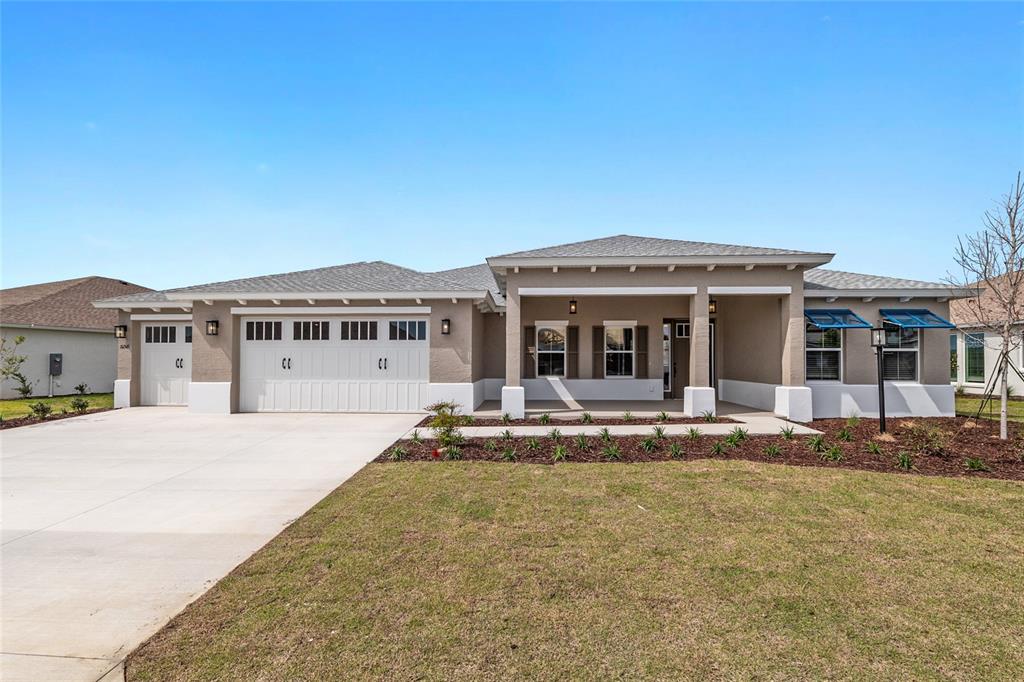 A single-story house with a beige stucco exterior, a three-car garage, and a covered porch — 10345 SW 82ND PLACE ROAD, OCALA, FL