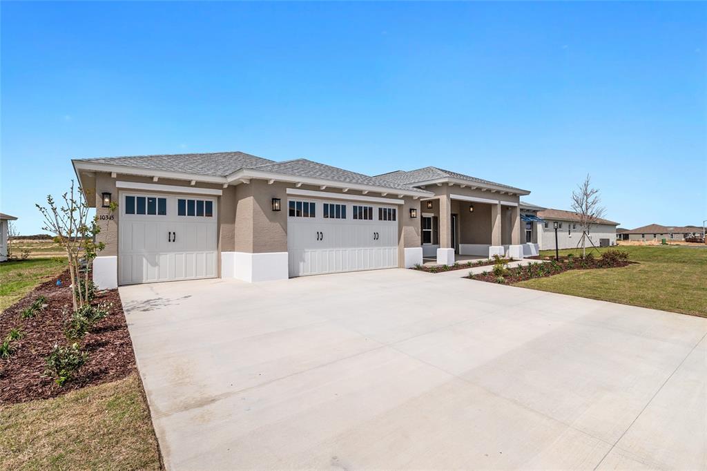 A single-story house features a three-car garage, a concrete driveway, and a covered entryway — 10345 SW 82ND PLACE ROAD, OCALA, FL