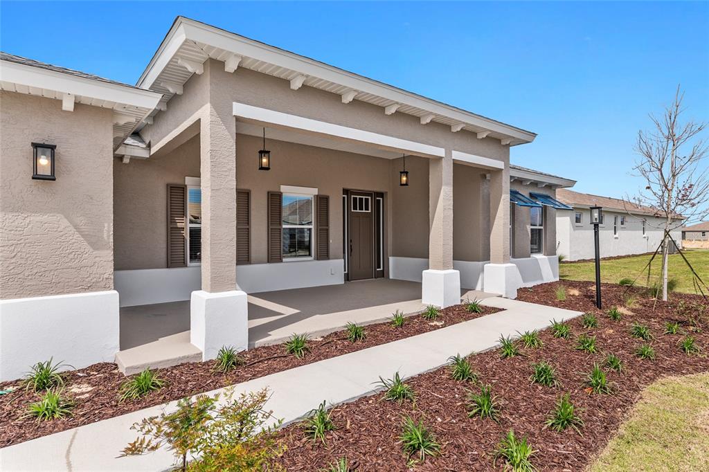A beige house exterior features a covered front porch, brown shutters, and a concrete walkway — 10345 SW 82ND PLACE ROAD, OCALA, FL