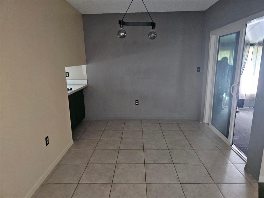 A dining area features gray walls, tile flooring, a modern pendant light, and sliding glass doors — 569 HUNTER CIRCLE, KISSIMMEE, FL