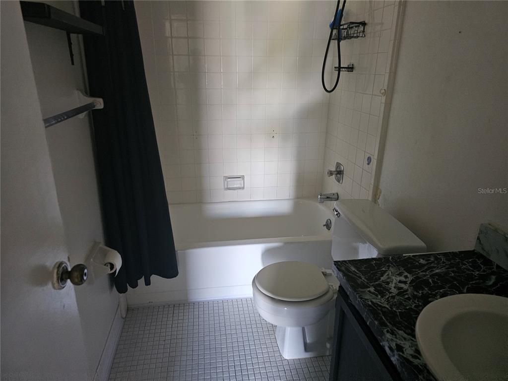 A small bathroom features a white tiled shower-tub combination, a toilet, and a vanity — 569 HUNTER CIRCLE, KISSIMMEE, FL