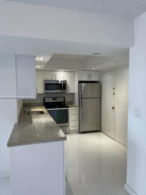 A kitchen features white cabinets, granite countertops, stainless steel appliances, and light-colored tile flooring — 3800 S Ocean Dr # 1725, Hollywood FL 33019, HOLLYWOOD, FL