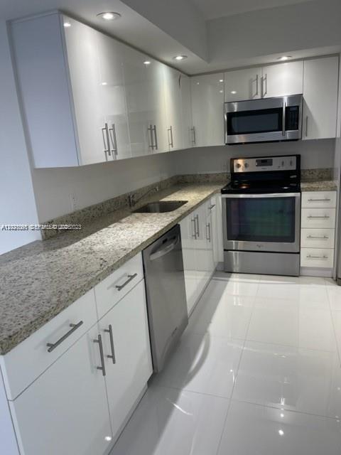 A modern kitchen features white glossy cabinets, granite countertops, and stainless steel appliances — 3800 S Ocean Dr # 1725, Hollywood FL 33019, HOLLYWOOD, FL