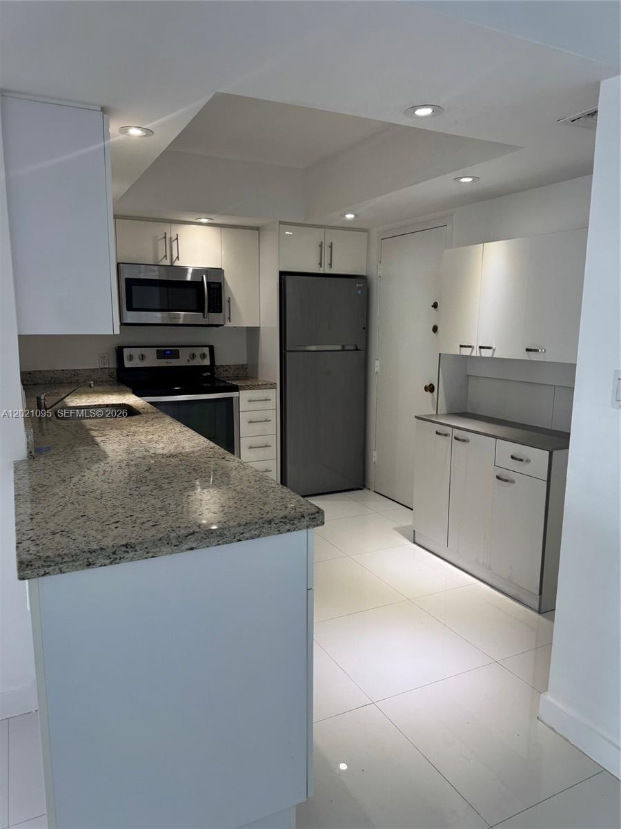 A kitchen features white cabinets, granite countertops, stainless steel appliances, and light tile flooring — 3800 S Ocean Dr # 1725, Hollywood FL 33019, HOLLYWOOD, FL