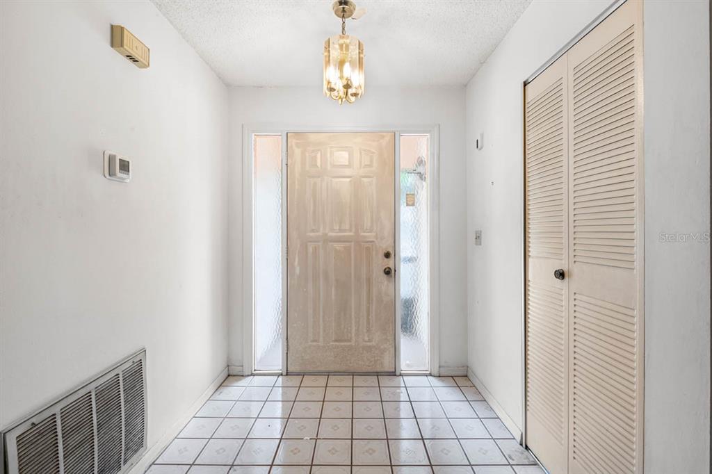 An entryway features white walls, a tiled floor, a central light fixture, and a closet — 1760 ATRIUM DRIVE, SUN CITY CENTER, FL
