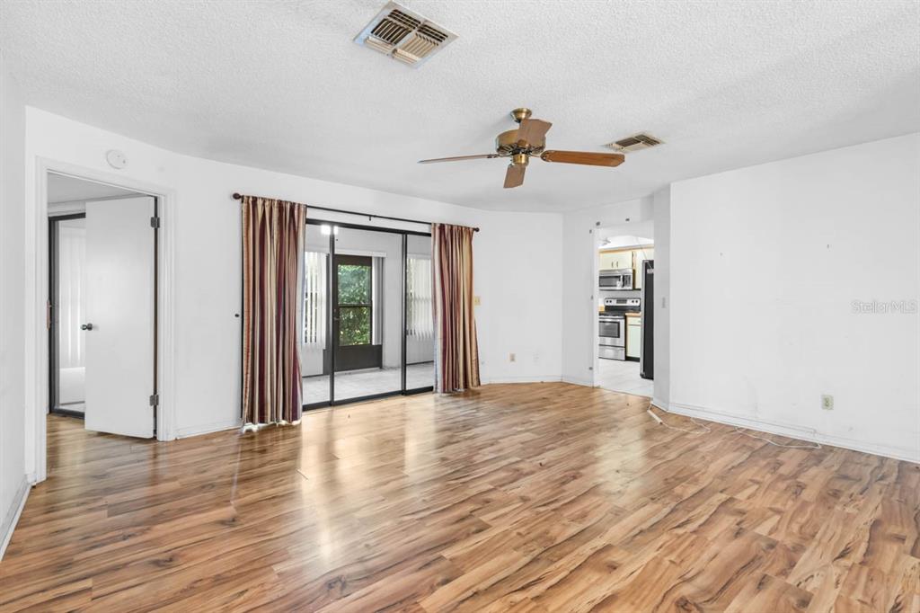 A living room with wood-look flooring, a ceiling fan, and sliding glass doors to a patio — 1760 ATRIUM DRIVE, SUN CITY CENTER, FL