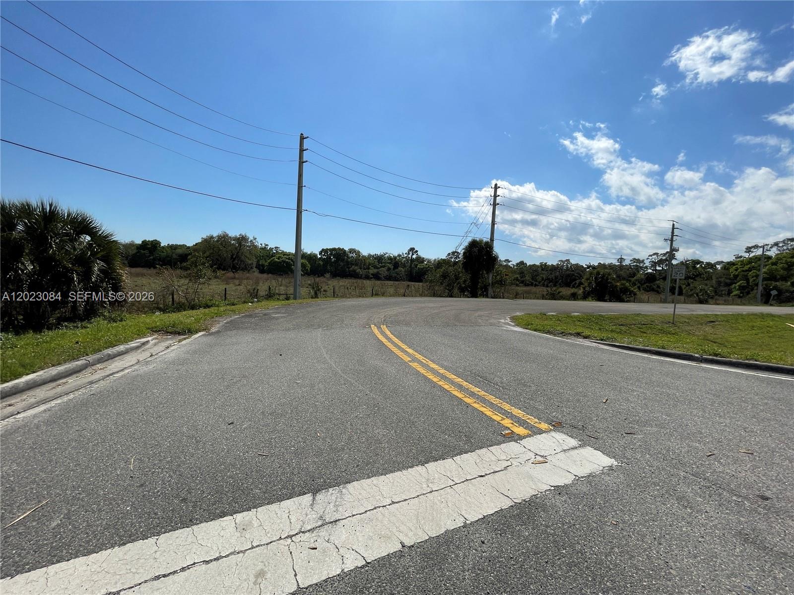 An asphalt road curves past a grassy field under a bright blue sky — 2358 E SR 70, Okeechobee FL 34972, OKEECHOBEE, FL