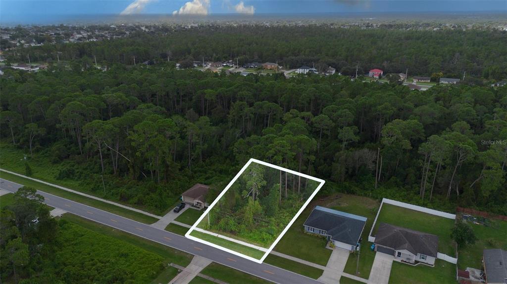 An aerial view shows a vacant, wooded residential lot outlined in white between two houses — 2657 CAPTAIN DRIVE, DELTONA, FL