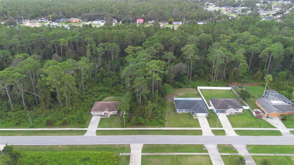 An aerial view shows two houses situated along a road with a large wooded area behind — 2657 CAPTAIN DRIVE, DELTONA, FL