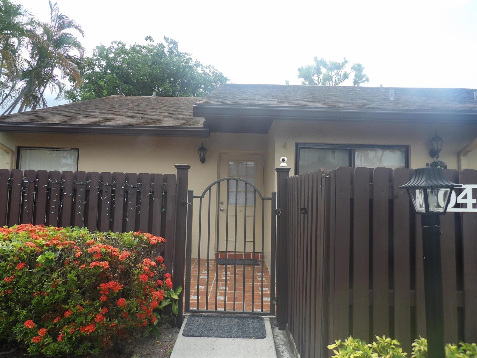 A brown wooden fence surrounds a gated entryway with a tiled patio and front door — 604 Sea Pine Way # A, FL 33415, FL