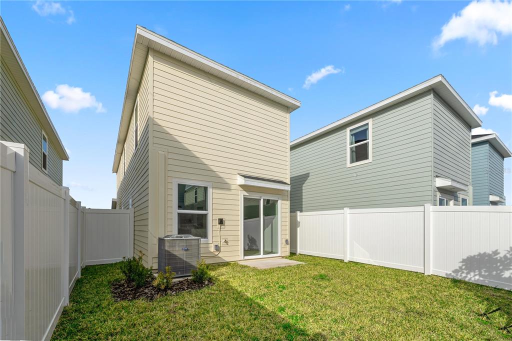The backyard of a two-story house features a small lawn, vinyl fencing, and an AC unit — 7212 SW 91ST LANE, OCALA, FL