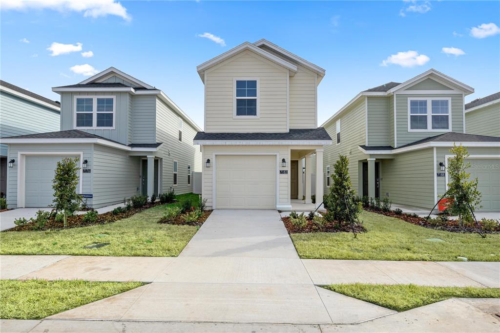 Three two-story suburban houses with light-colored siding and attached garages stand side-by-side — 7212 SW 91ST LANE, OCALA, FL
