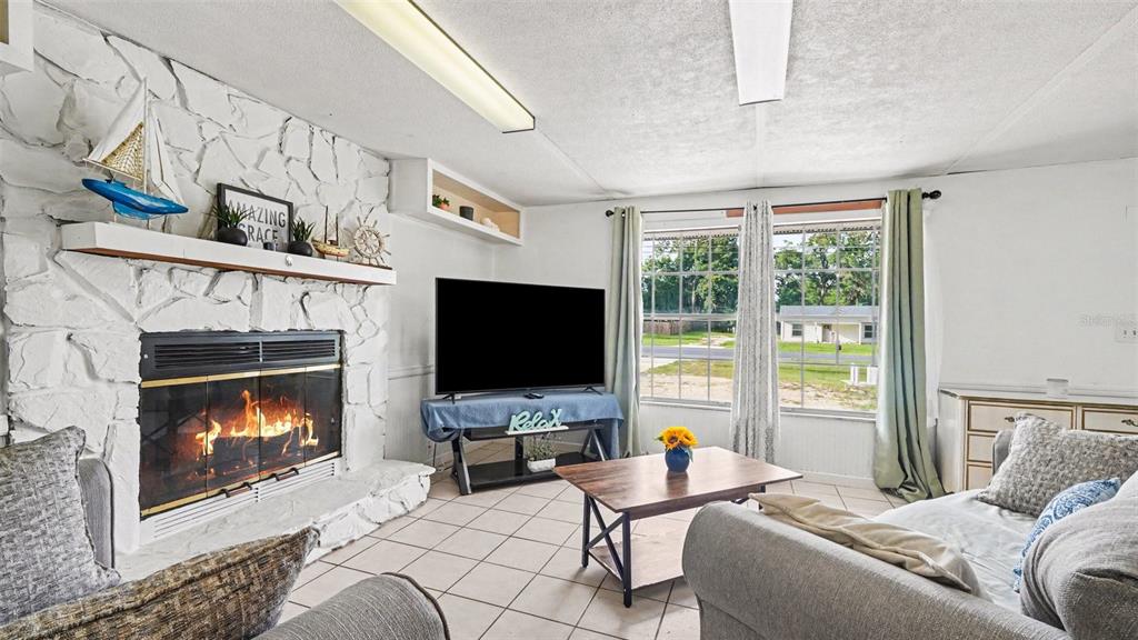 A living room features a white stone fireplace, tile flooring, and a large window — 7075 W HOMOSASSA TRAIL, HOMOSASSA, FL