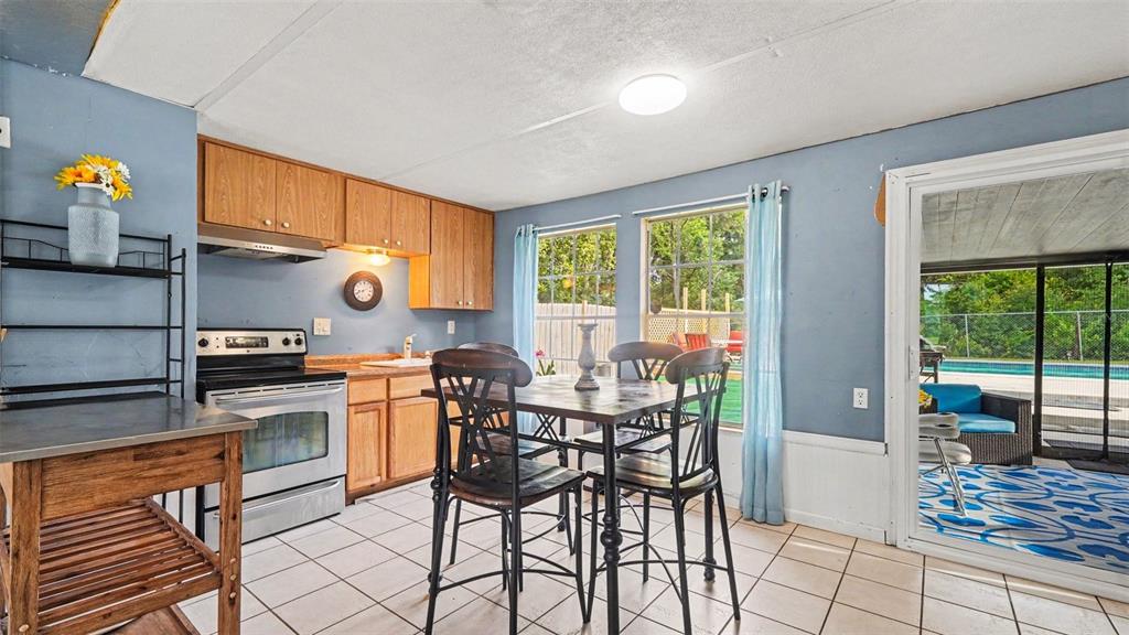 A kitchen with wood cabinets, tile floors, and a dining table overlooks a backyard pool — 7075 W HOMOSASSA TRAIL, HOMOSASSA, FL