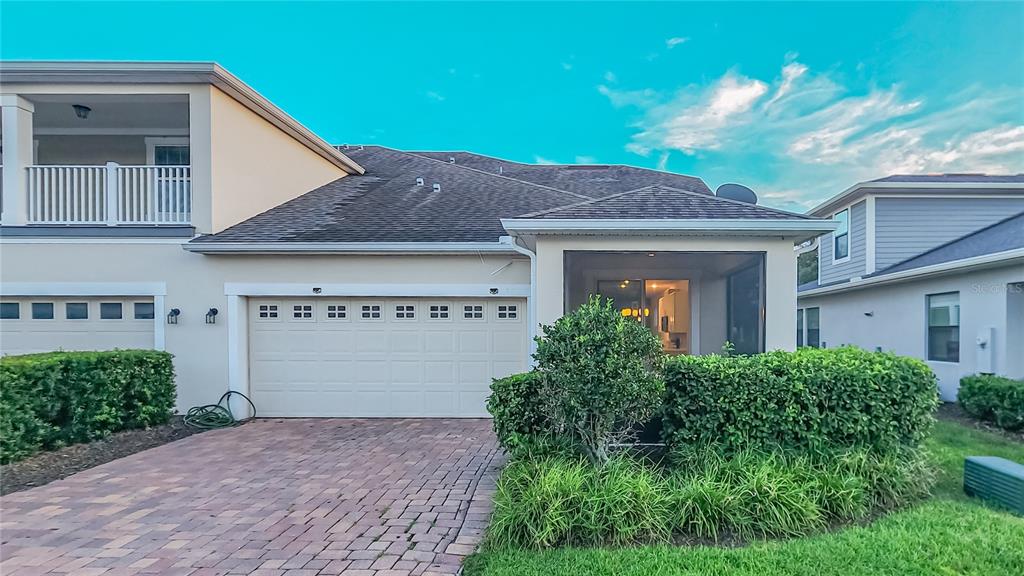 A beige house exterior features a two-car garage, a screened-in patio, and a paved driveway — 2945 CELLO LANE, KISSIMMEE, FL