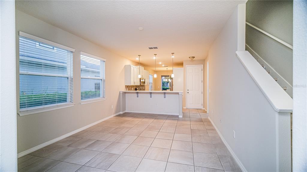 A tiled dining area features a breakfast bar, white kitchen cabinets, and a staircase — 2945 CELLO LANE, KISSIMMEE, FL