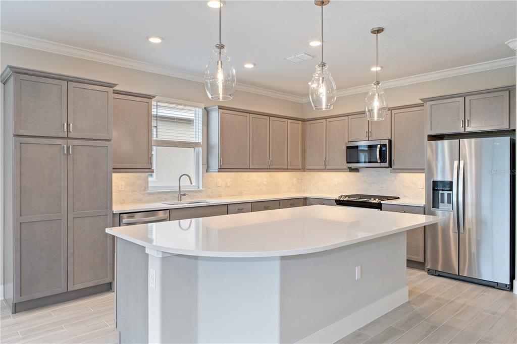 A kitchen with gray cabinets, white countertops, stainless steel appliances, and a large center island — 4516 NW 54TH TERRACE, OCALA, FL