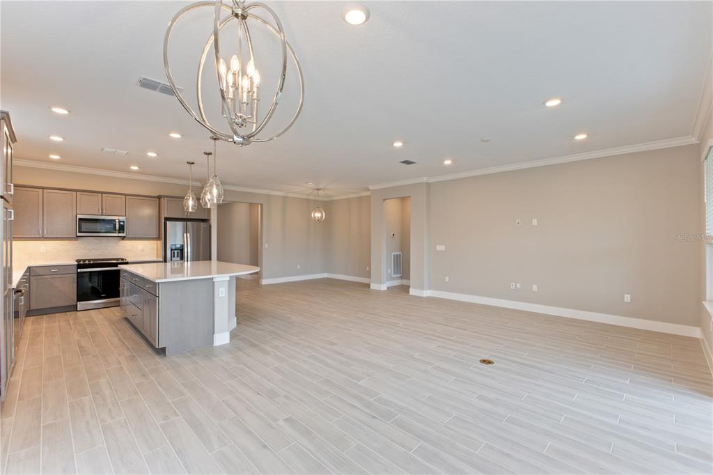 A kitchen with gray cabinets and a large island opens into a spacious living area — 4516 NW 54TH TERRACE, OCALA, FL