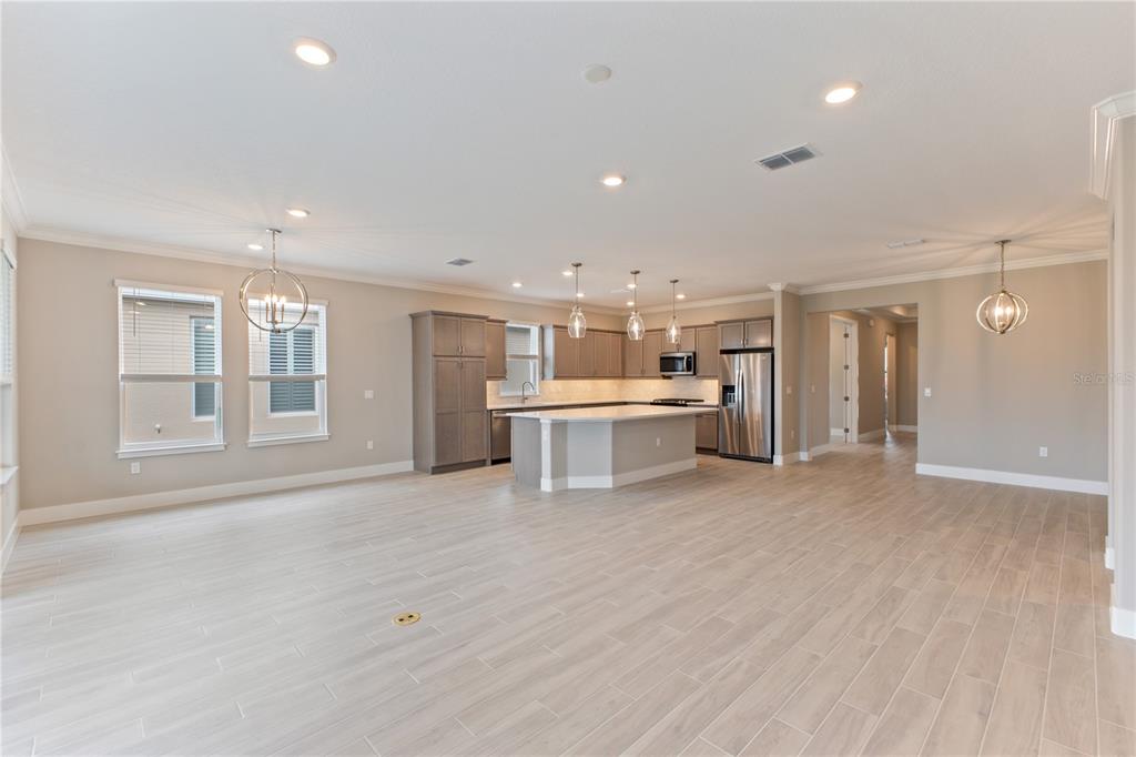 An open-concept kitchen features light wood-look tile flooring, gray cabinetry, and a central island — 4516 NW 54TH TERRACE, OCALA, FL