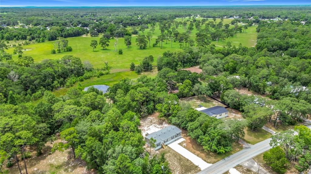 An aerial view shows two houses surrounded by trees and a large open field — 6498 W ROSEDALE DRIVE, HOMOSASSA, FL