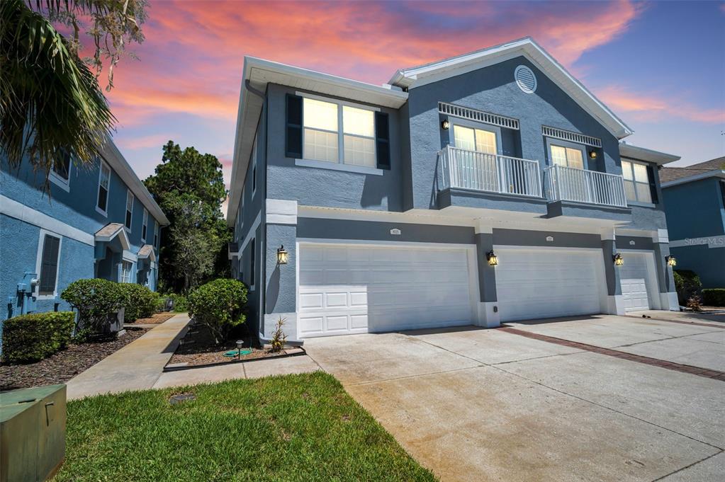A two-story blue townhouse with white trim, a multi-car garage, and a second-story balcony — 8525 SHALLOW CREEK, NEW PORT RICHEY, FL